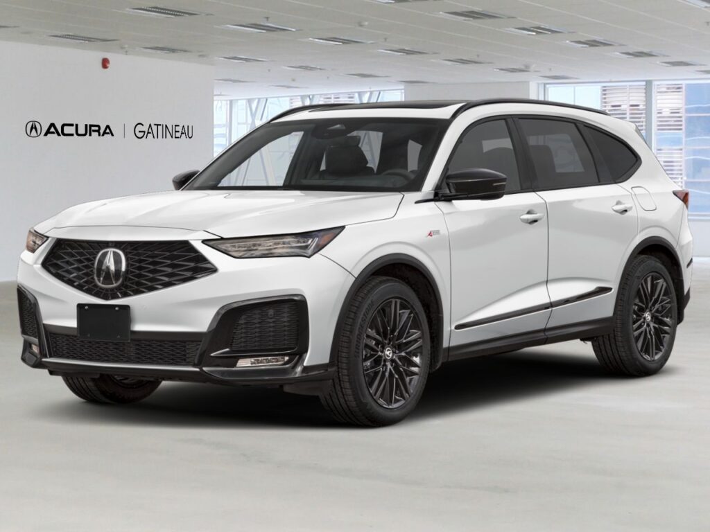 Acura MDX blanc stationné dans un studio lumineux, vue trois quarts avant, avec jantes noires, calandre diamant distinctive et logo Acura Gatineau visible en arrière-plan.